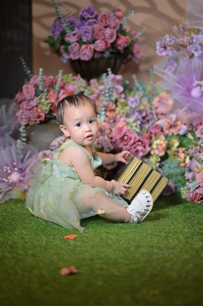 Tanya seated beside a gold and black box in the flower garden