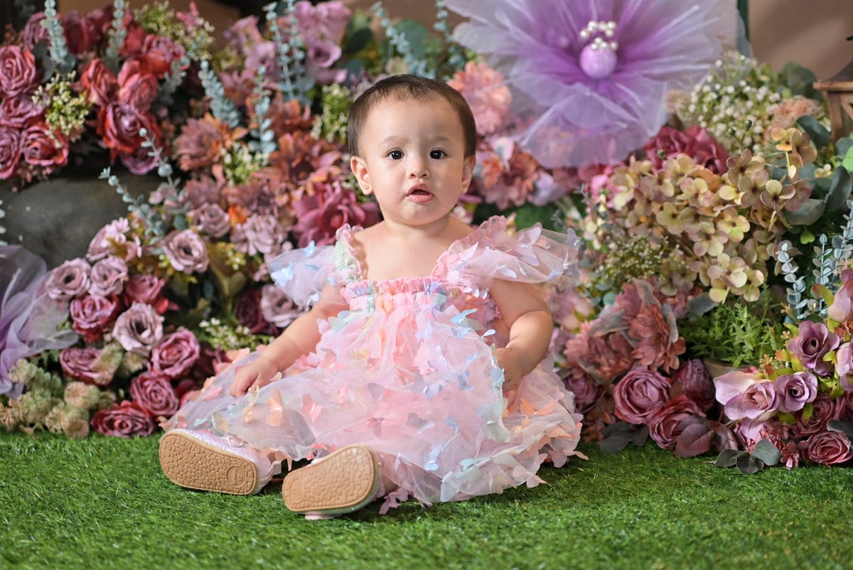 Tanya Czarene seated in a pastel butterfly dress surrounded by flowers